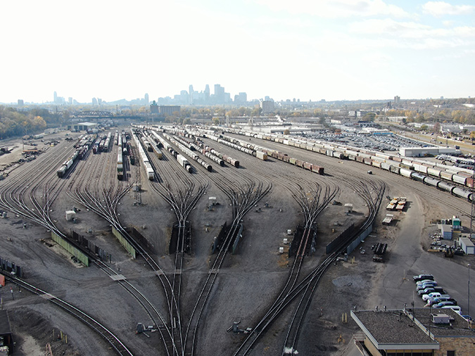 View of the Northtown hump yard, or “bowl,” with secondary retarders in foreground. Master retarder is below bottom edge of photo. Downtown Minneapolis is visible in background.