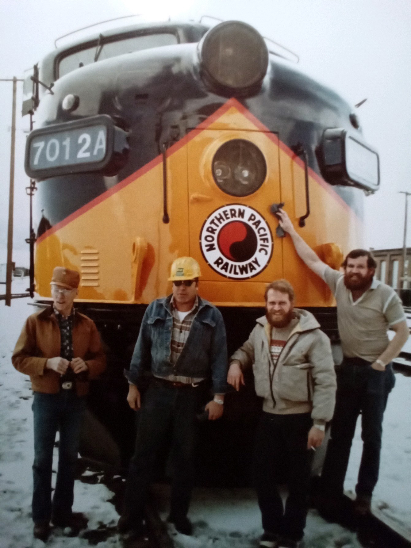 Bill Hampson, left, standing in front of a Northern Pacific Railway locomotive with three colleagues