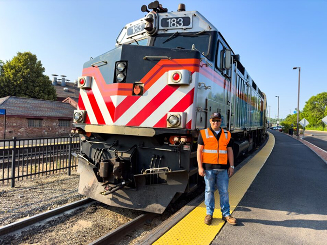 Molina in front of a Metra commuter train at the Aurora, Illinois, passenger station