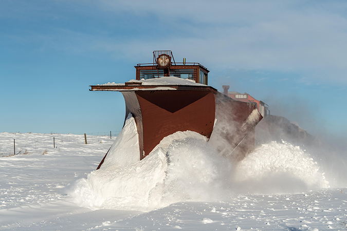 A Russell, or Flier, snowplow clearing out a path on a sunny day.