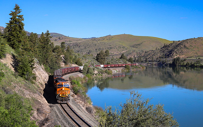 A Tier 4 locomotive leads a grain train eastbound along the Flathead River.